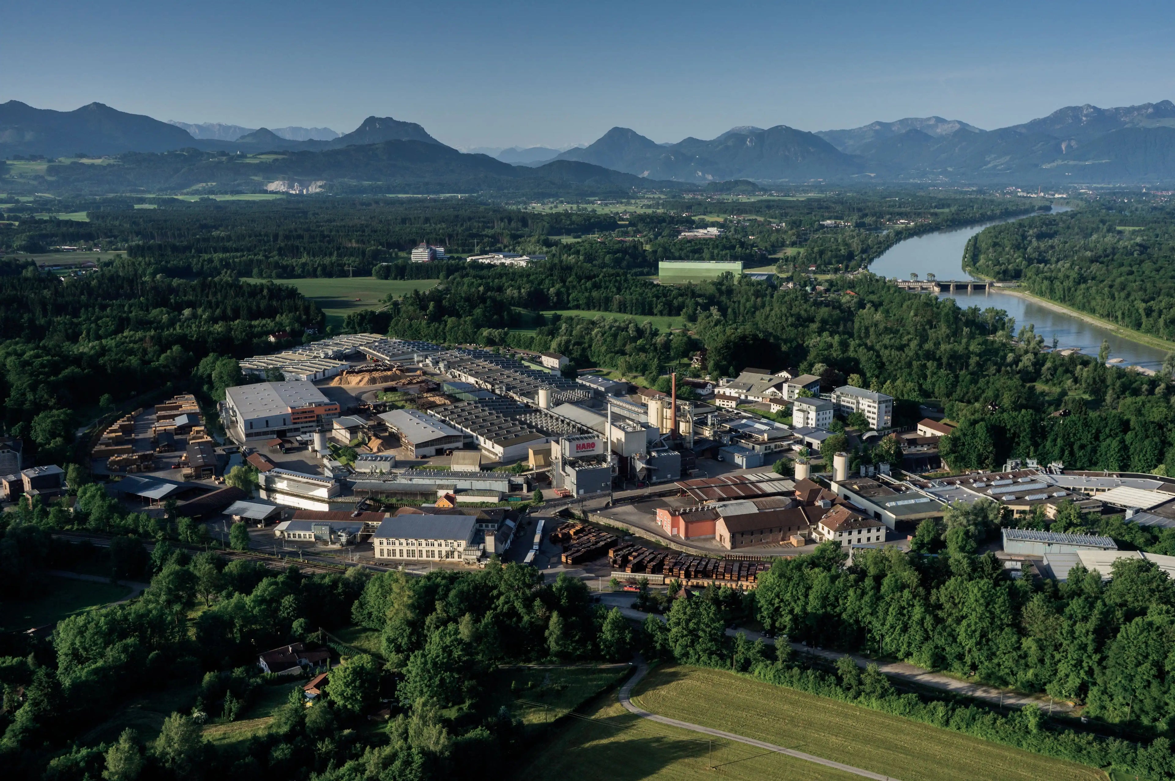 Luftaufnahme des Hamberger Firmenkomplexes mit Fluss im Hintergrund, die eine malerische Landschaft zeigt.